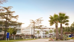 Ein mehrstöckiges Hotel mit Innenhof, der Palmen und einen Spielplatz zeigt.