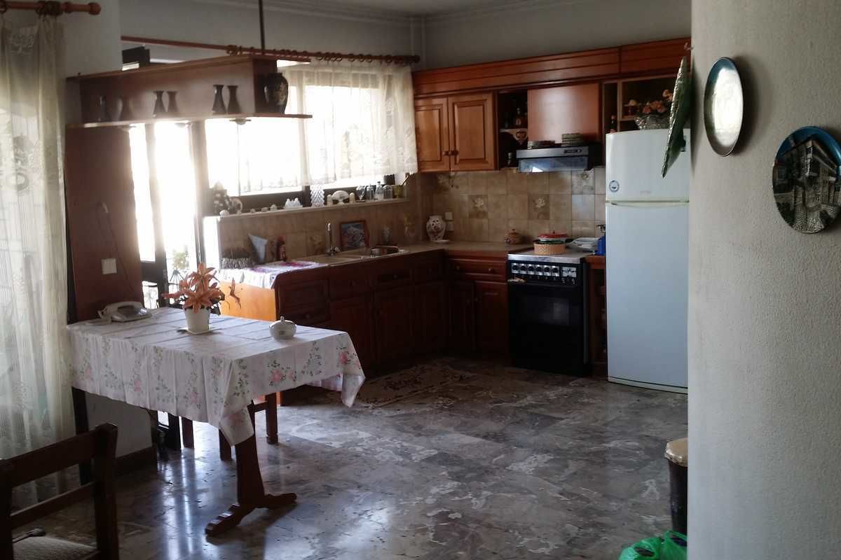 A kitchen with wooden cabinets, a refrigerator, a dishwasher, and a dining table with a floral tablecloth.