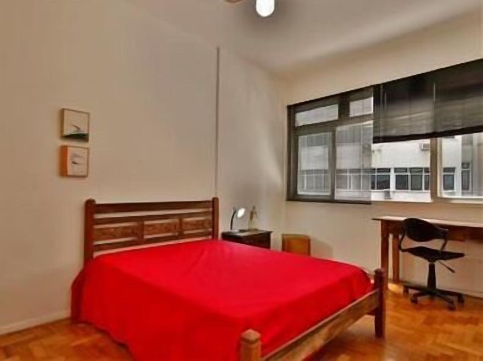 A bedroom with a wooden bed, a desk, and a chair.
