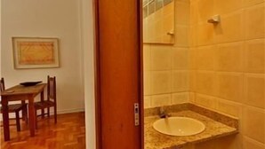 Un baño con lavamanos, espejo, suelo de madera y un cuadro en la pared.