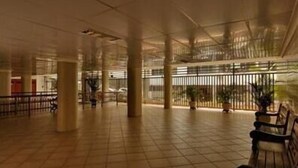 Un espacio interior amplio con suelo de baldosas, bancos y plantas en macetas.
