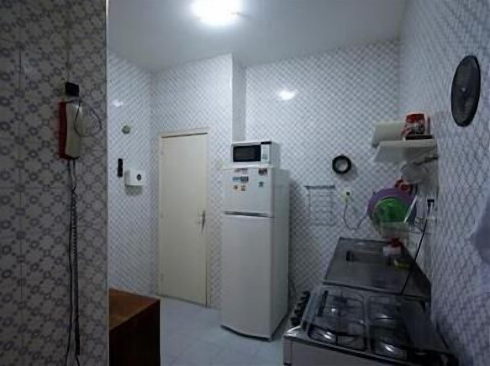 A small kitchen with a refrigerator, microwave, and gas stove.