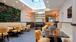 Un restaurante moderno con pared verde, asientos acolchados y tragaluces.