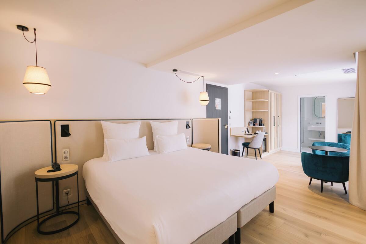 A modern hotel room with a large bed, bedside tables, a desk, and a chair.