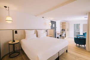 A modern hotel room with a large bed, bedside tables, a desk, and a chair.