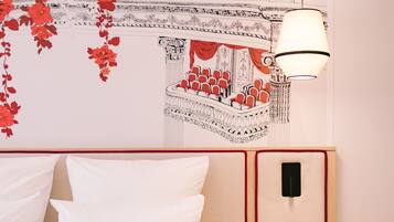 Una habitación de hotel con una cama, una mesa redonda y un mural en la pared.