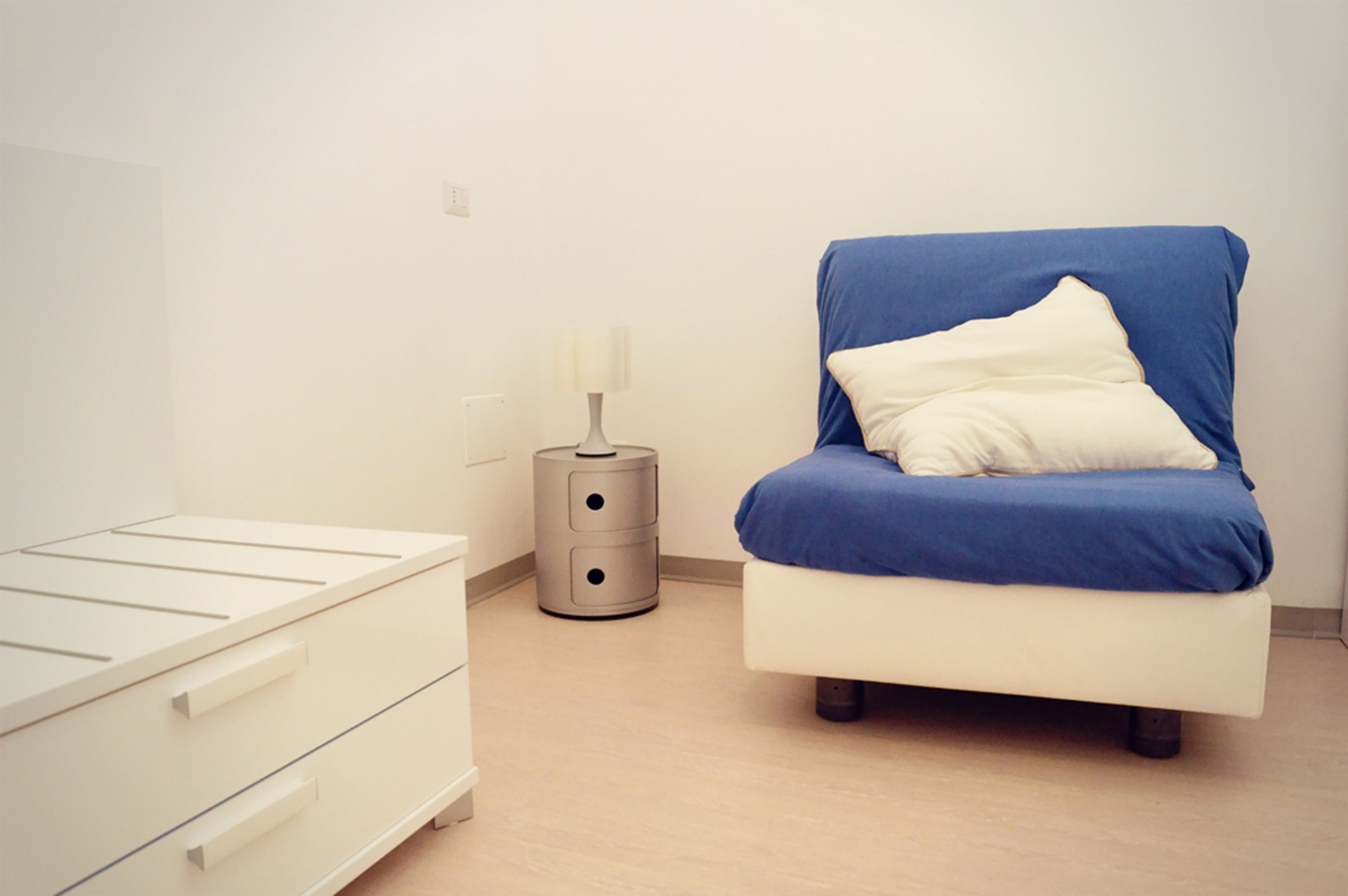 A bedroom with a bed, a bedside table, and a lamp.