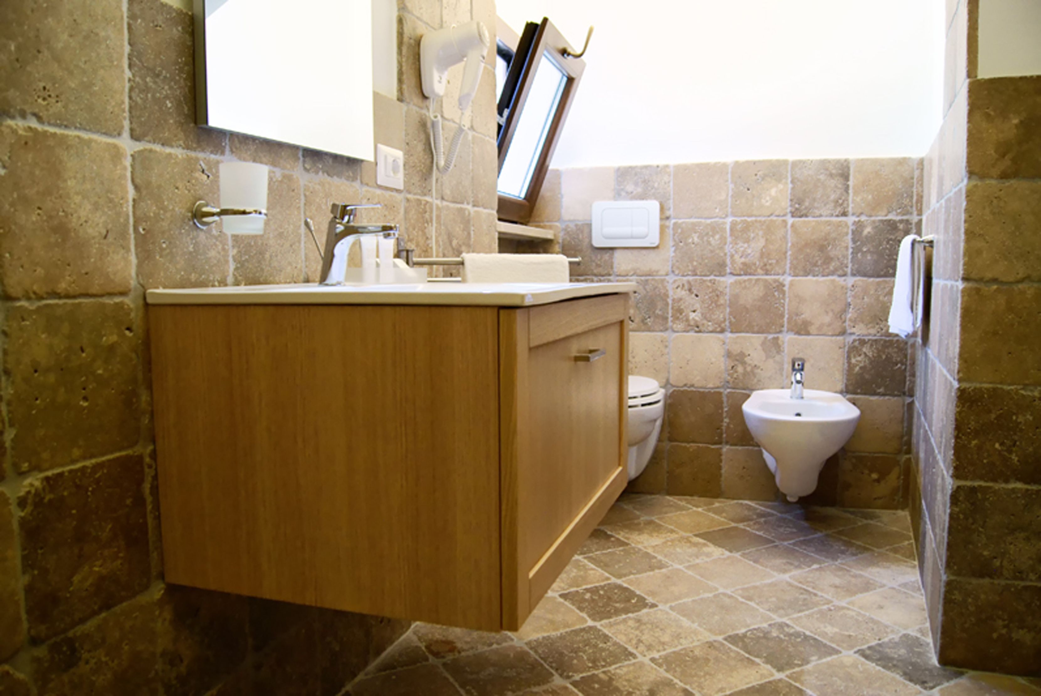 A bathroom with a wooden vanity, a toilet, and a bidet.