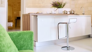 Una cocina moderna con una isla blanca, un sofá verde y una pared de piedra.
