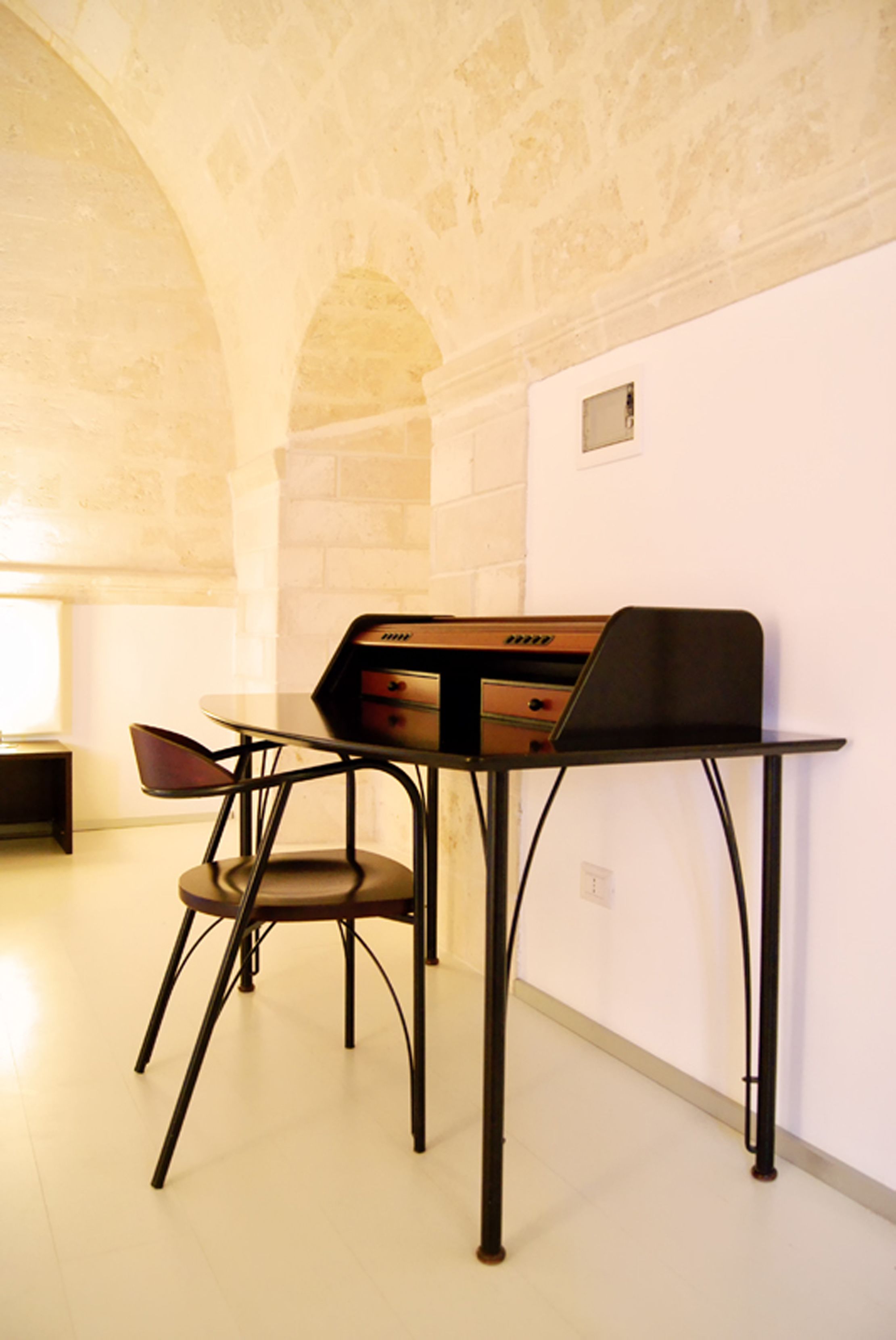 Una habitación con una mesa, una silla, un piano y una pared de piedra.