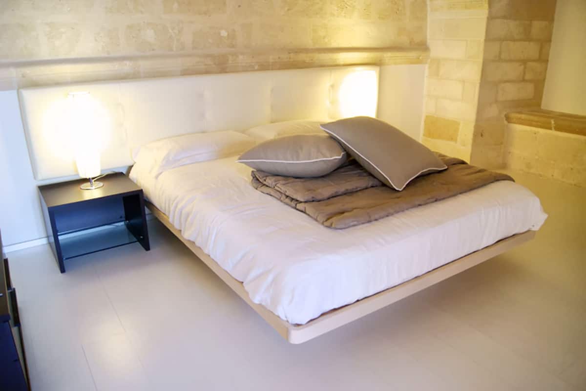 A neatly made bed with pillows and a bedside table with a lamp.