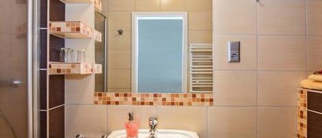 A bathroom with a white sink, a mirror, and a tiled wall.