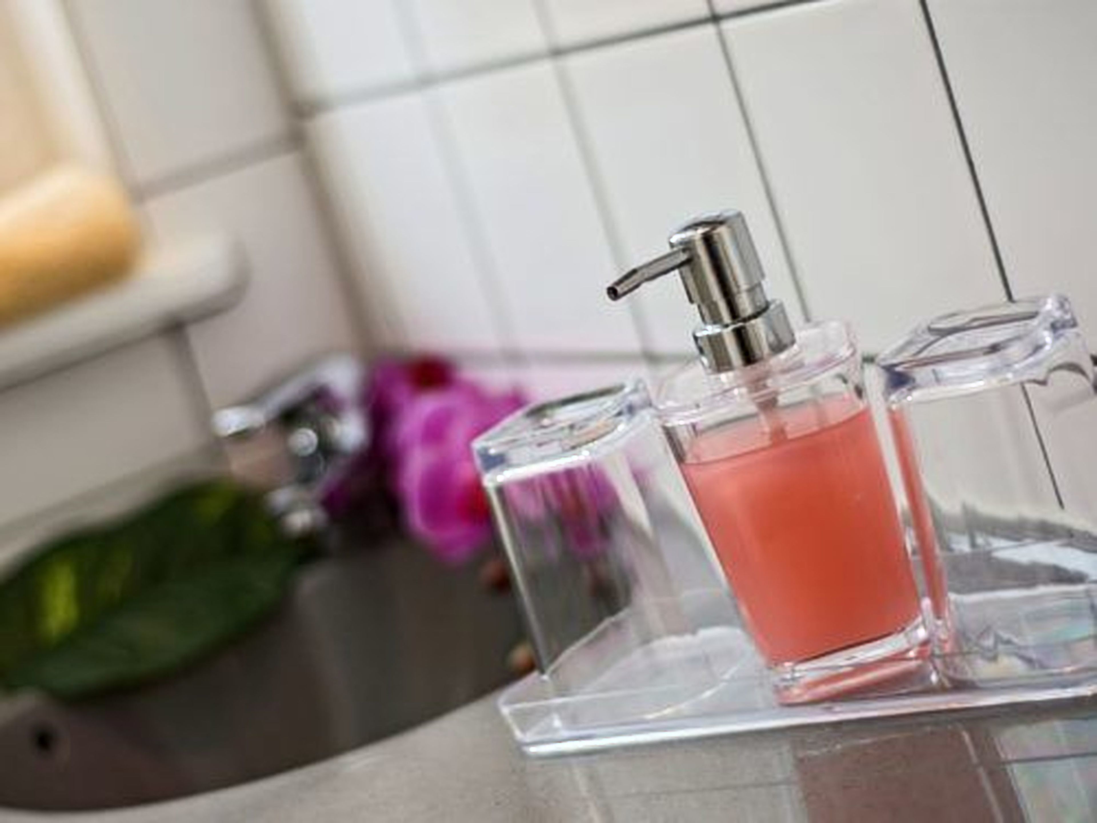 A bathroom with a clear glass perfume bottle on a white sink.
