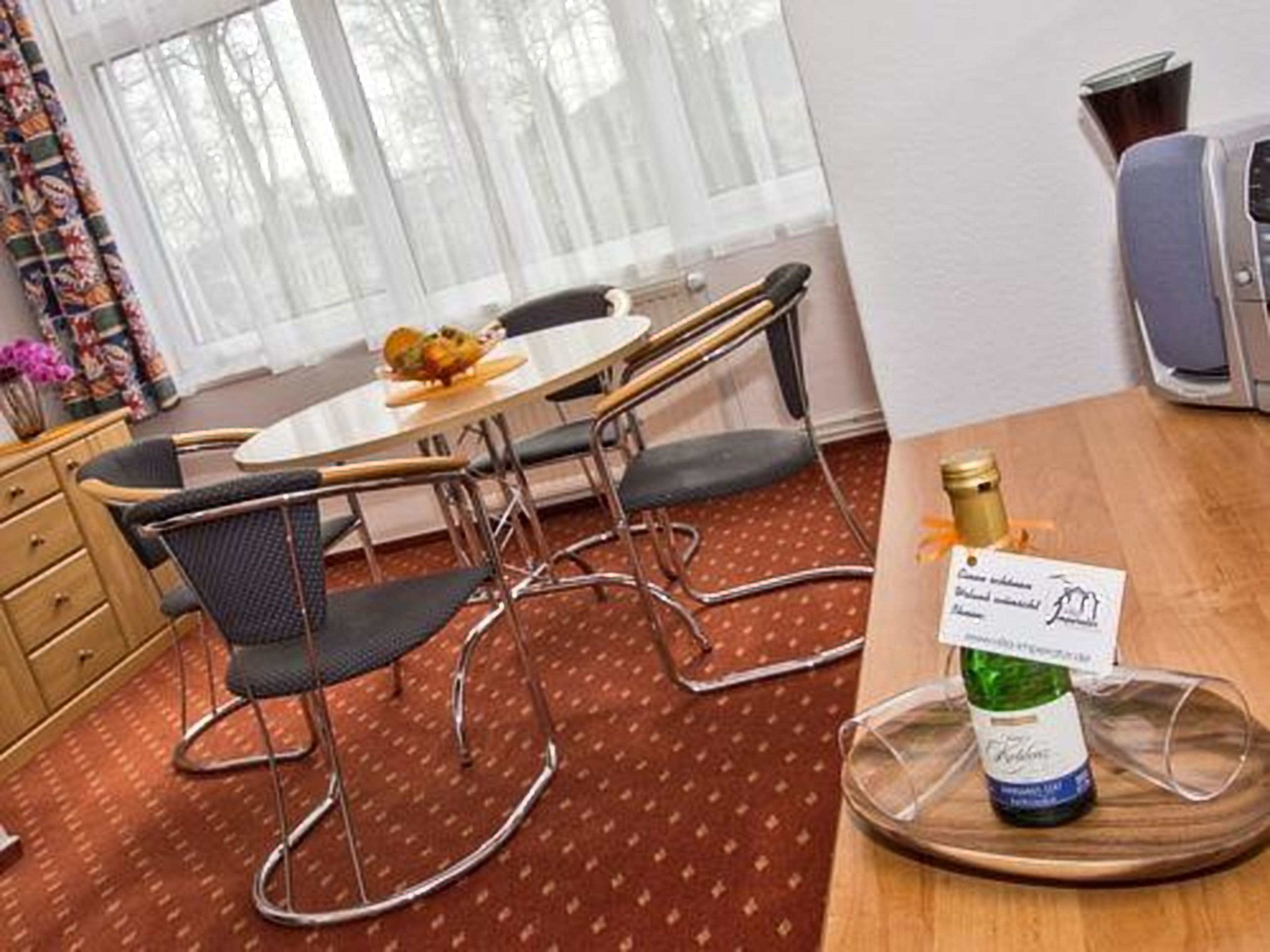 A dining area with a table, chairs, and a bottle of wine on a coaster.