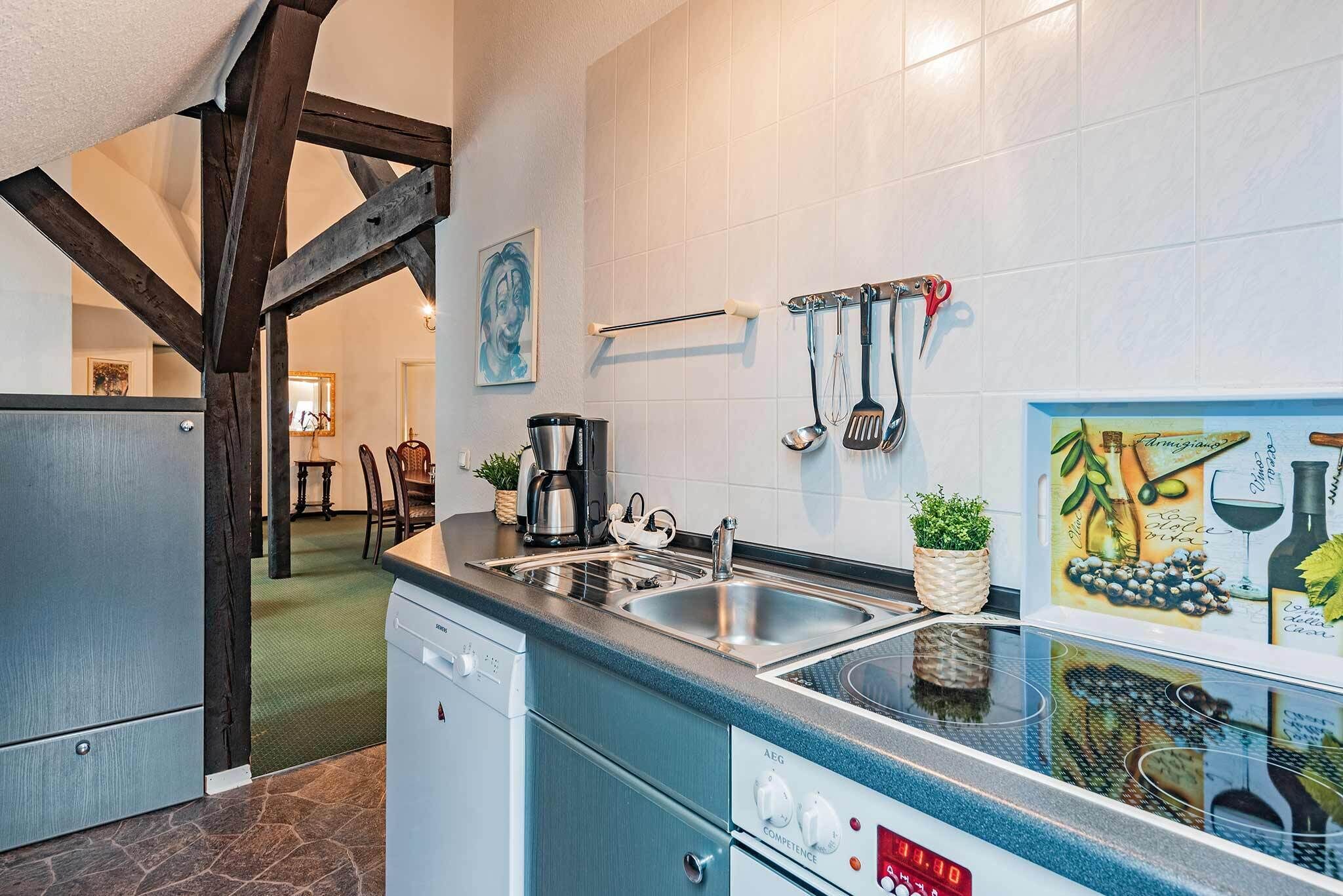 Eine moderne Küche mit Geschirrspüler, Spüle und Kaffeemaschine. Es gibt hängendes Kochgeschirr und ein Bild an der Wand.