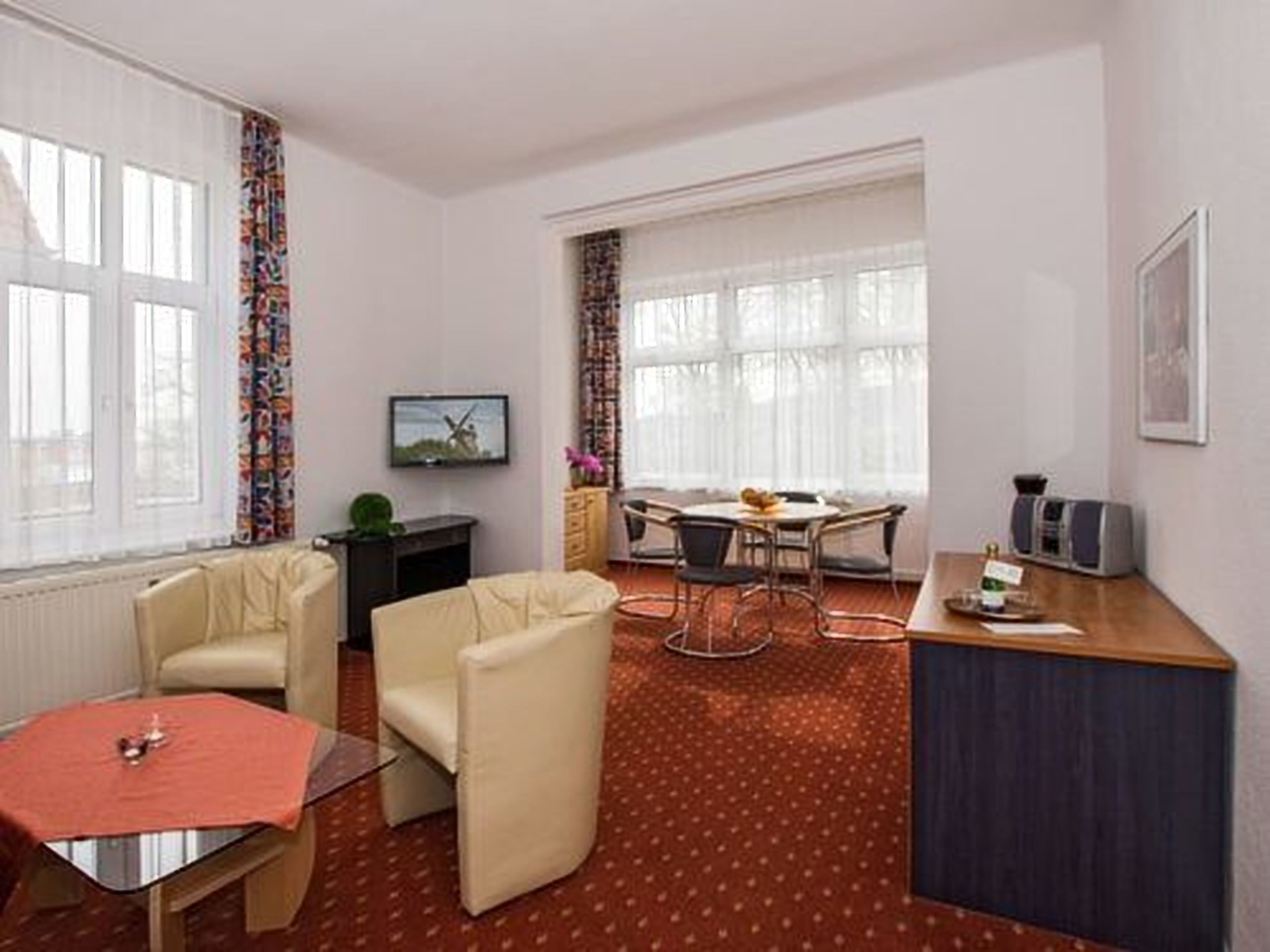 A hotel room with a dining area, a TV, a desk, and a chair.