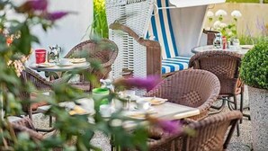 Un espace extérieur aménagé avec des meubles en osier et un parasol à rayures.