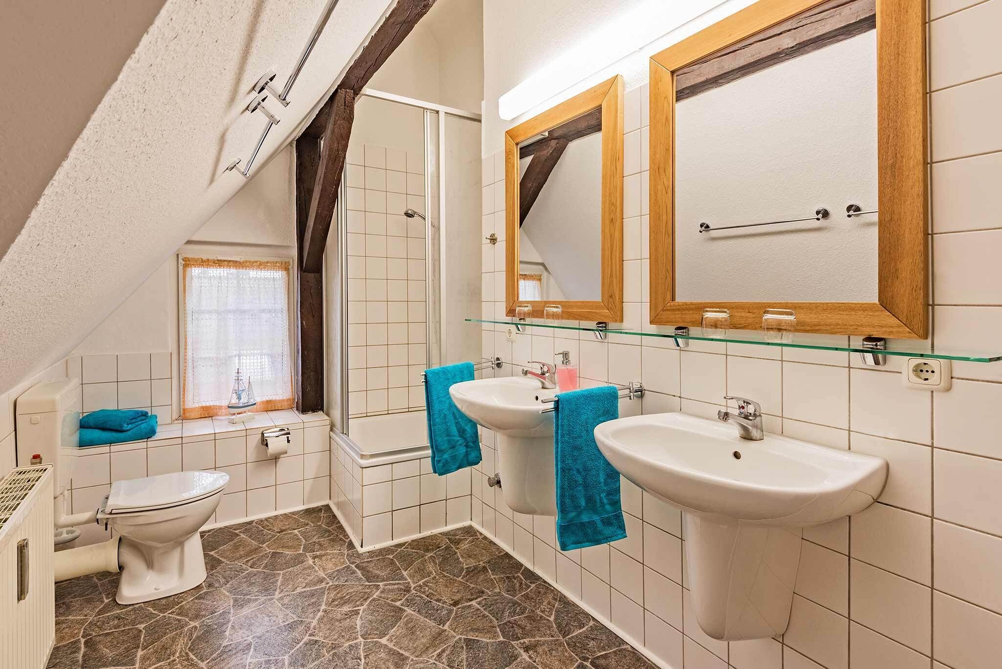 Un baño con inodoro, dos lavamanos y ducha.
