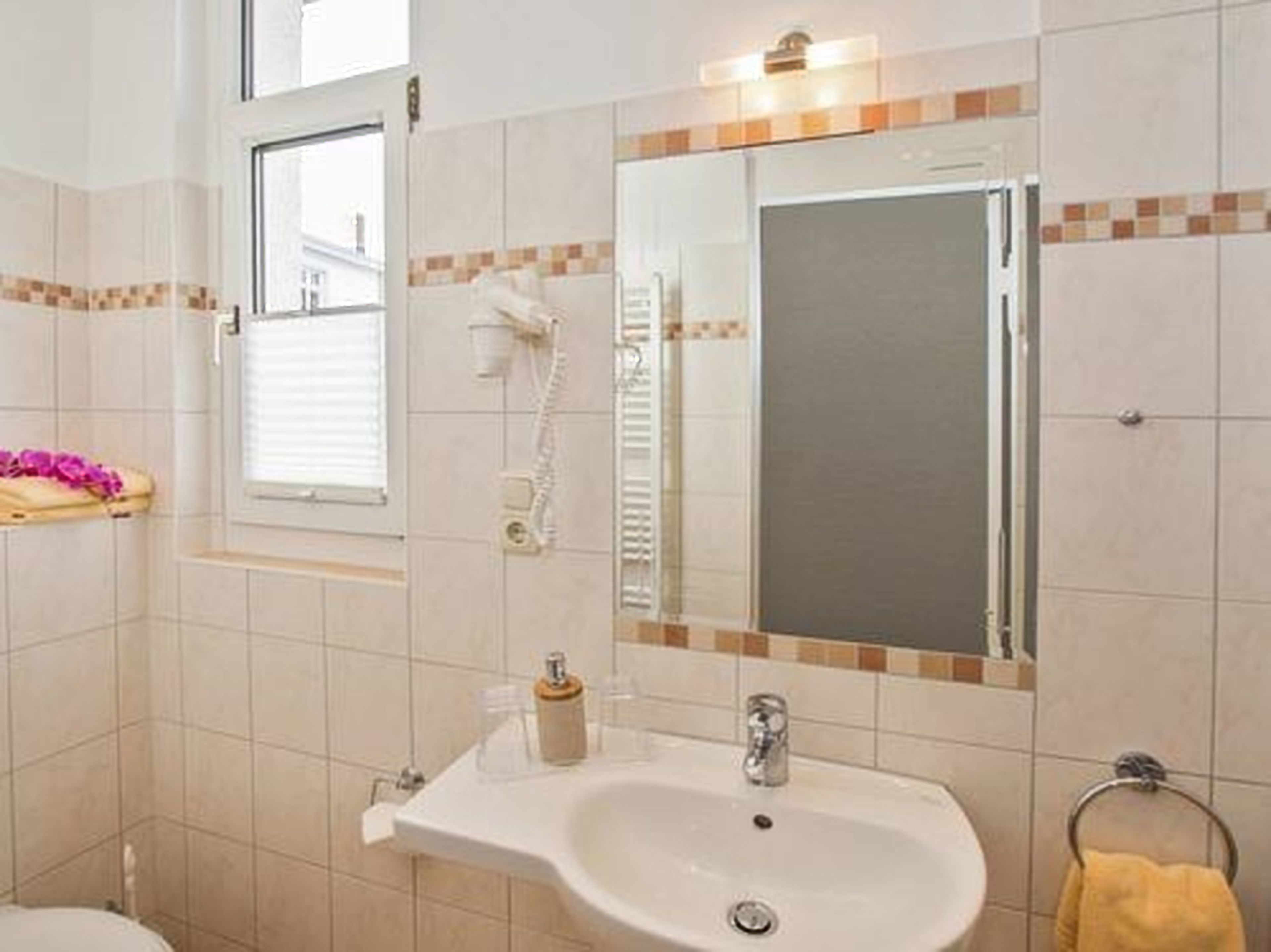 A bathroom with a sink, mirror, and towel rack.