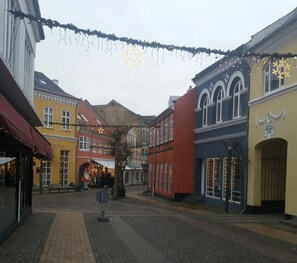 A cobblestone street lined with colorful buildings, some with visible signage. - B & B Hygge (Tranekaer)