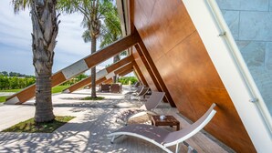 A modern outdoor lounge area with sun loungers and a large wooden structure. - Casale delle Ronde B&B (Latina)