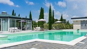 A swimming pool with lounge chairs and umbrellas, surrounded by tall trees and a clear sky. - Casale delle Ronde B&B (Latina)
