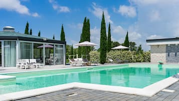 Una piscina al aire libre, sillones reclinables de piscina