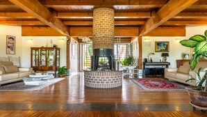 A spacious living room with a central fireplace, wooden beams, a large mirror, and a leather sofa. - Casale delle Ronde B&B (Latina)