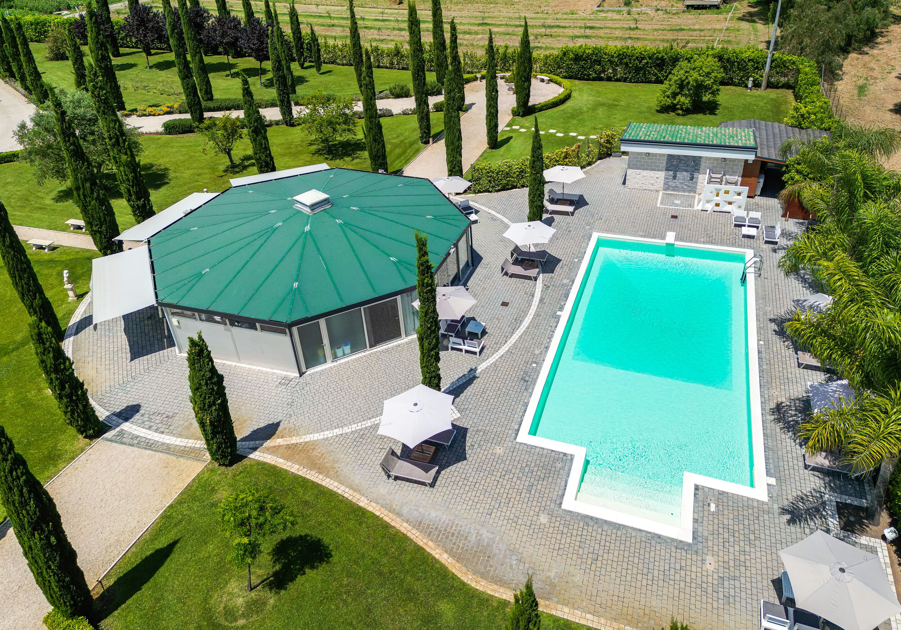 An aerial view of a resort with a swimming pool, lounge area, and landscaped garden.