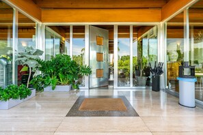 Una entrada moderna con puertas de cristal, plantas en macetas y un piso de baldosas limpias.