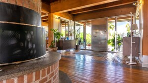A spacious room with a fireplace, wooden flooring, and large windows offering a view of the outdoors. - Casale delle Ronde B&B (Latina)