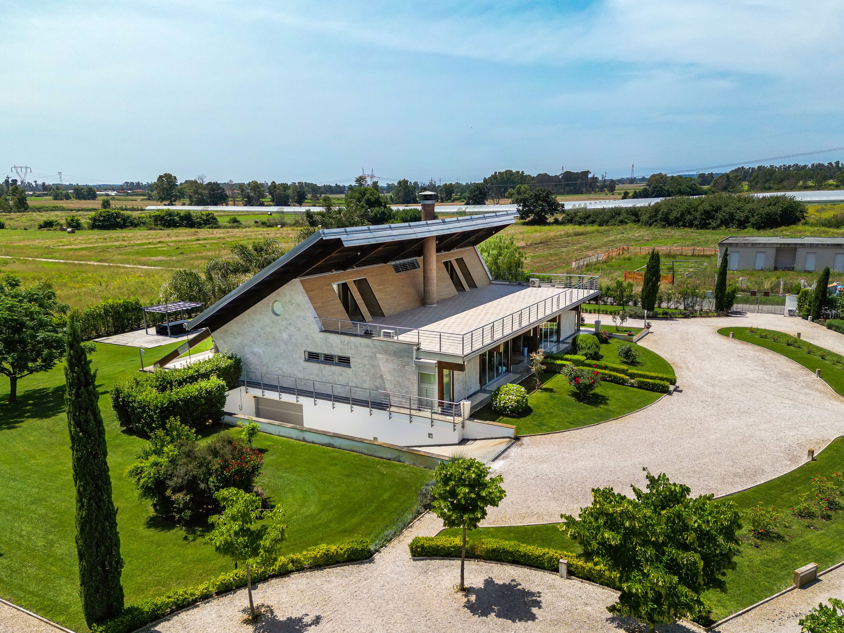 A modern house with a sloped roof, large windows, and a spacious outdoor area with a driveway and well-maintained lawn.