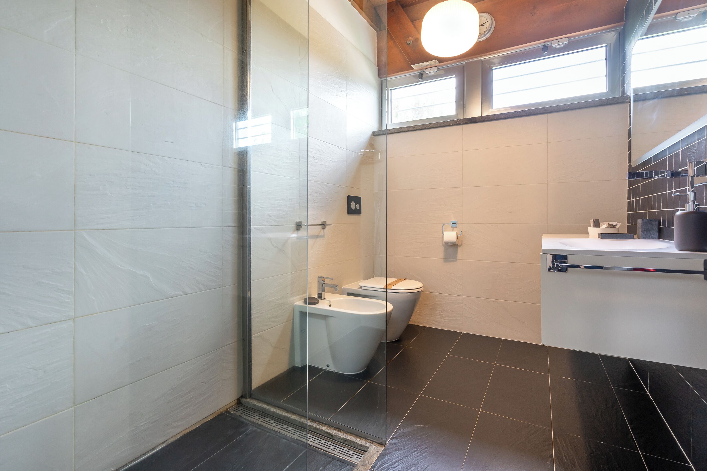 Een moderne badkamer met een douchecabine van glas, een toilet en een wastafel.