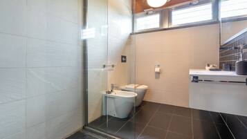 Een moderne badkamer met een douchecabine van glas, een toilet en een wastafel.