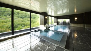 Una piscina interior con amplias ventanas que ofrecen vistas a un área boscosa.