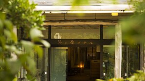 Un edificio con entrada de vidrio, un letrero con caracteres japoneses y plantas en macetas afuera.
