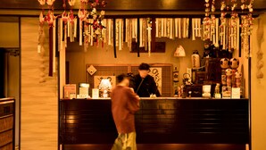Un área de recepción con mostrador de madera, adornos colgantes y estética tradicional japonesa.