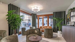 A modern lounge area with seating, a coffee machine, and large windows offering a view of the street. - Hotel Grifoni (Venice)