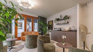 A modern living room with a sofa, armchairs, and a round table. There is a kitchen area with a sink and cabinets. - Hotel Grifoni (Venice)