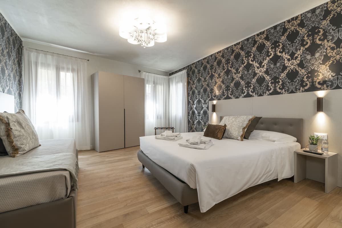 A modern bedroom with a large bed, bedside tables, and a chandelier.