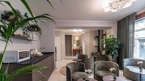 A modern living room with a kitchen area, including a microwave, chairs, and tables. - Hotel Grifoni (Venice)