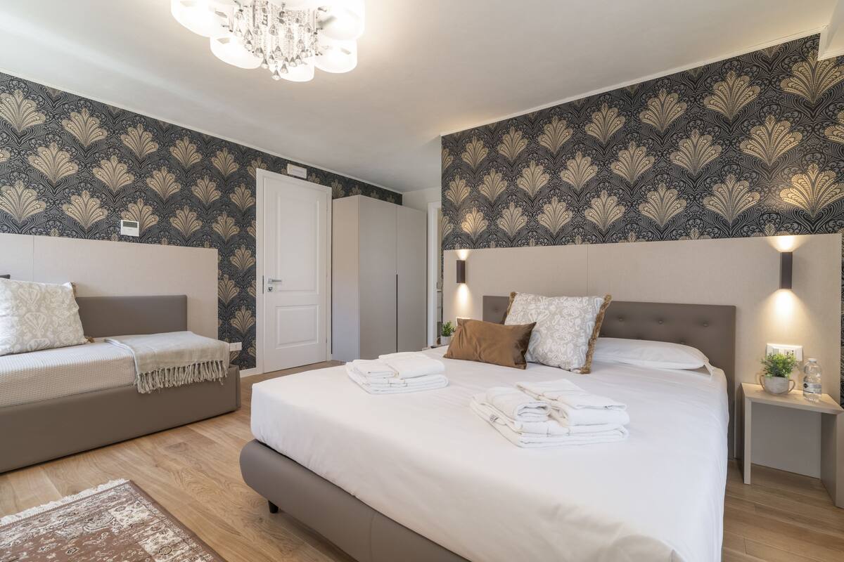 A modern bedroom with a large bed, a sofa, and a nightstand.