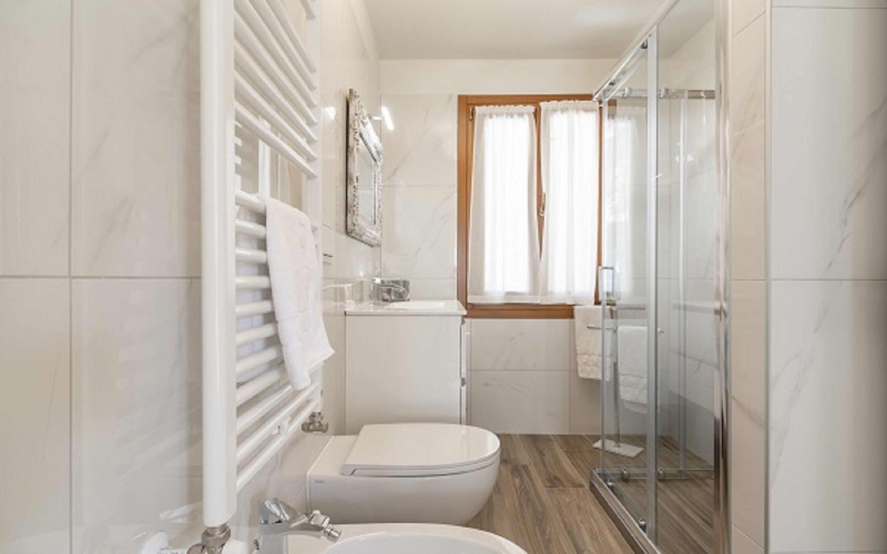 Un bagno moderno con il water, una cabina doccia in vetro e una finestra con tende.