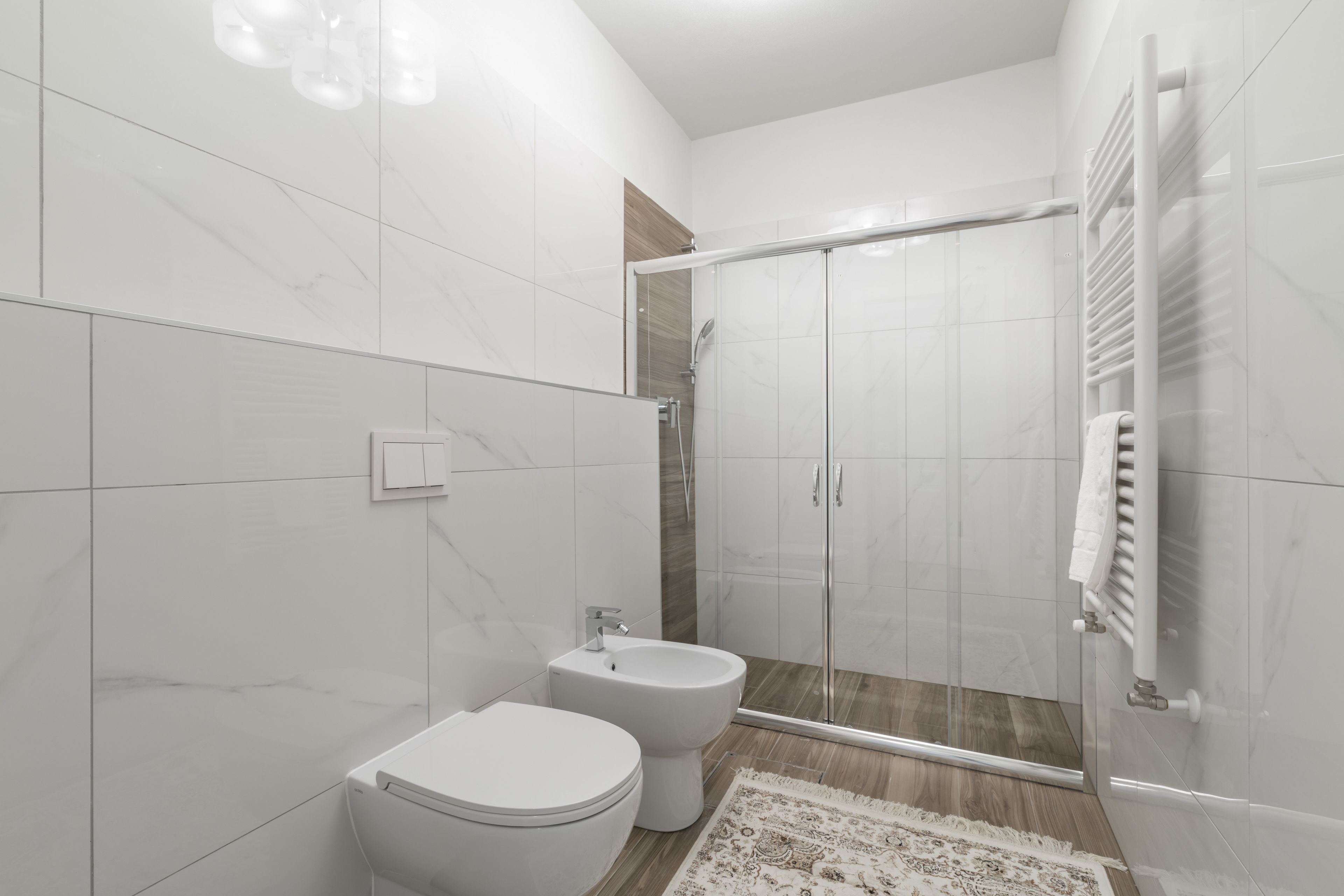 A modern bathroom with a toilet, bidet, and glass-enclosed shower.