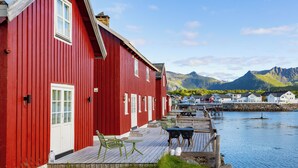 A red building with a wooden deck and outdoor seating. - Astra Village - Waterfront Rorbu Cabins in Lofoten (Vagan)
