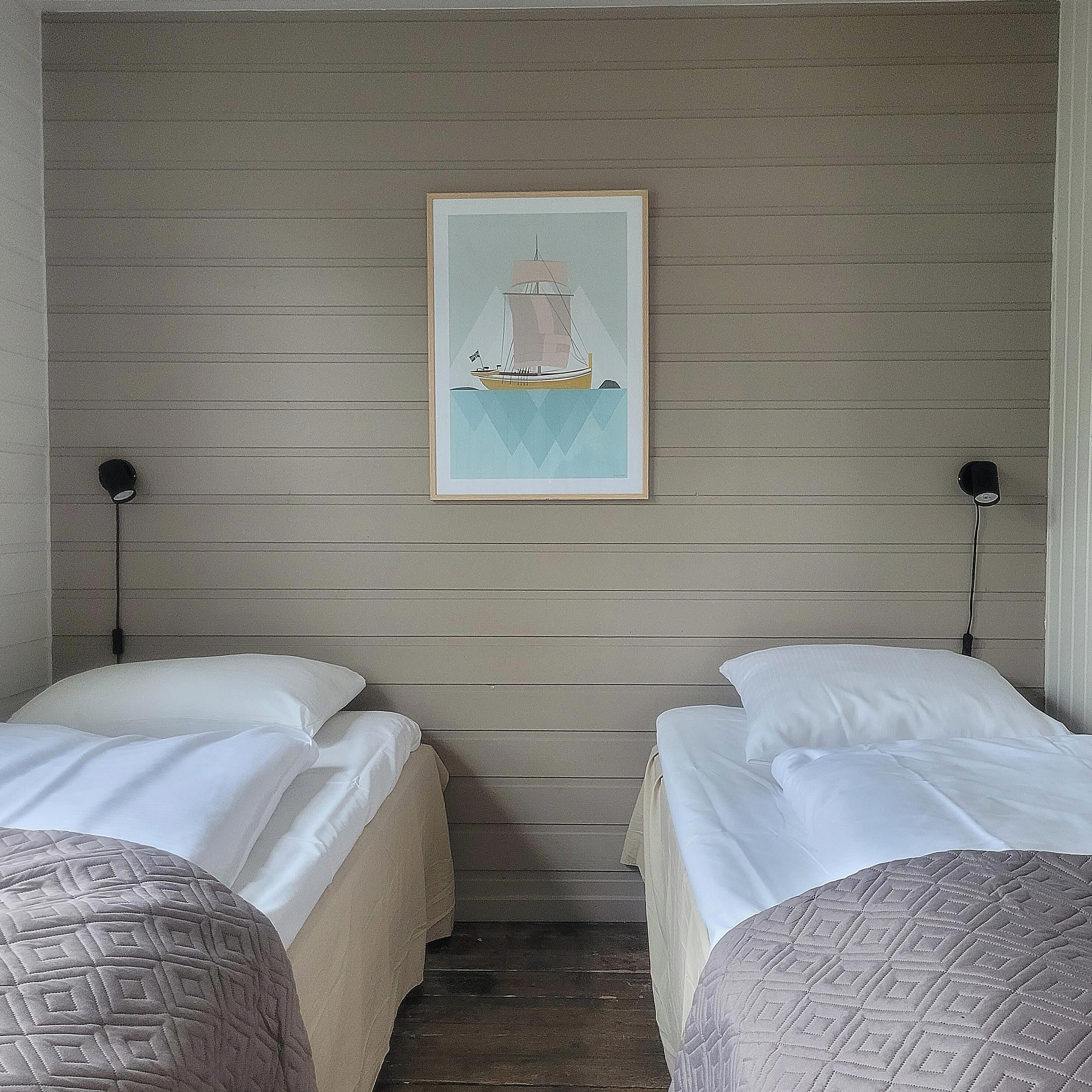 Camera d'albergo con due letti, un quadro appeso al muro e un pavimento in legno.