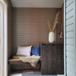 A corner room with a bench, pillows, a rustic cabinet, and a vase with dried plants. - Astra Village - Waterfront Rorbu Cabins in Lofoten (Vagan)