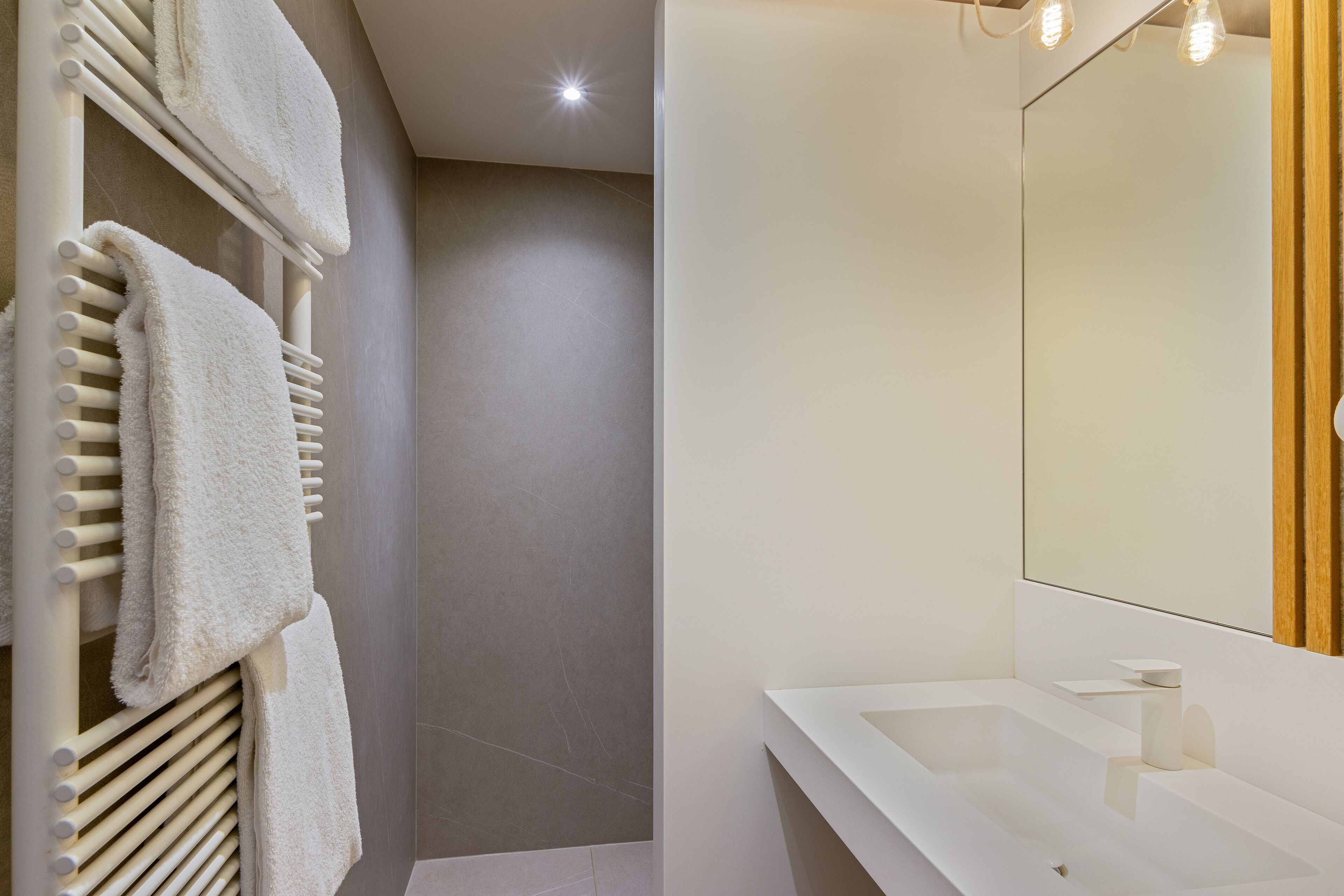 Un baño moderno con lavamanos, espejo y toallero blancos.