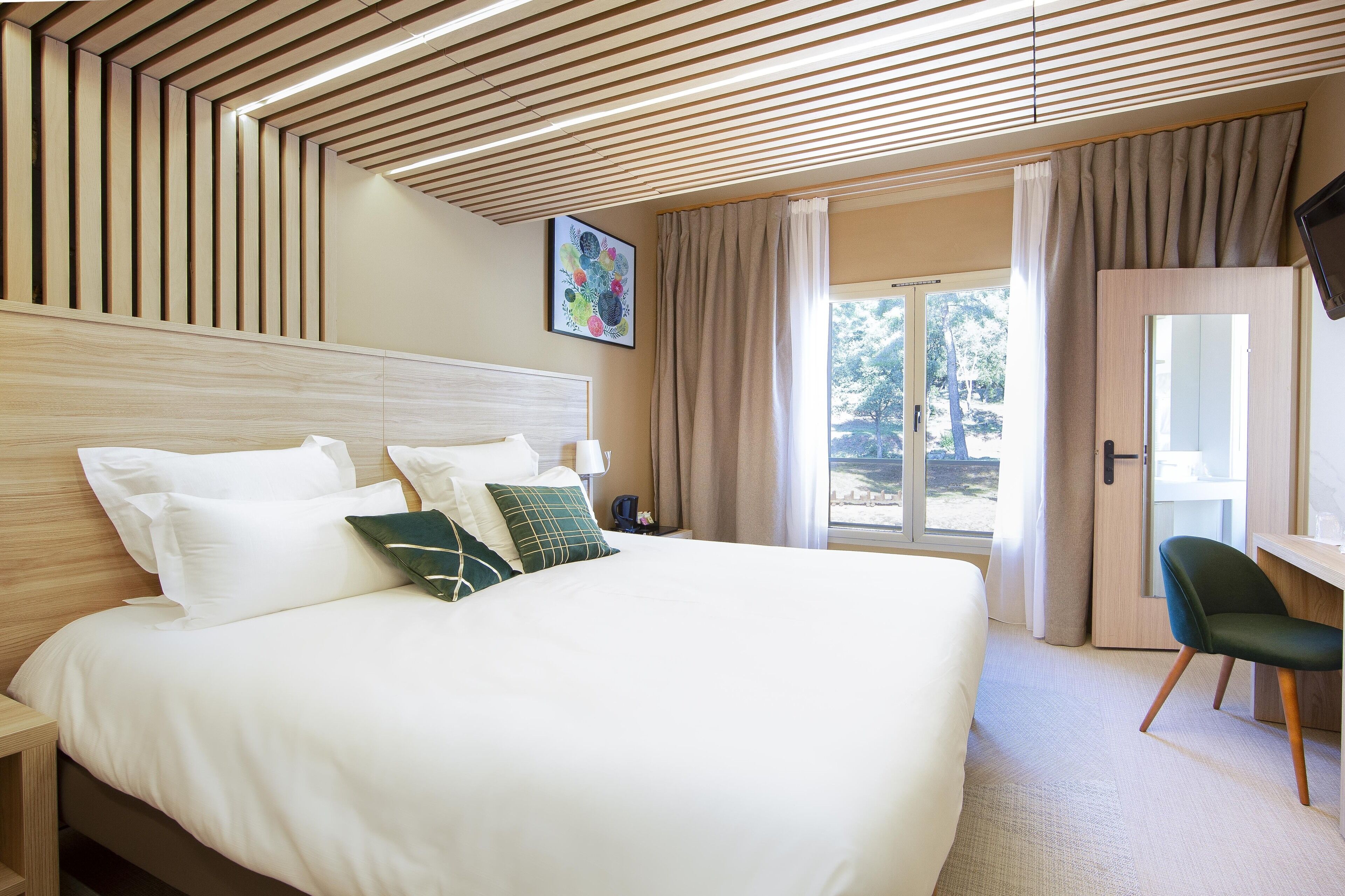 Habitación de hotel con una cama grande, un escritorio y vistas al exterior.