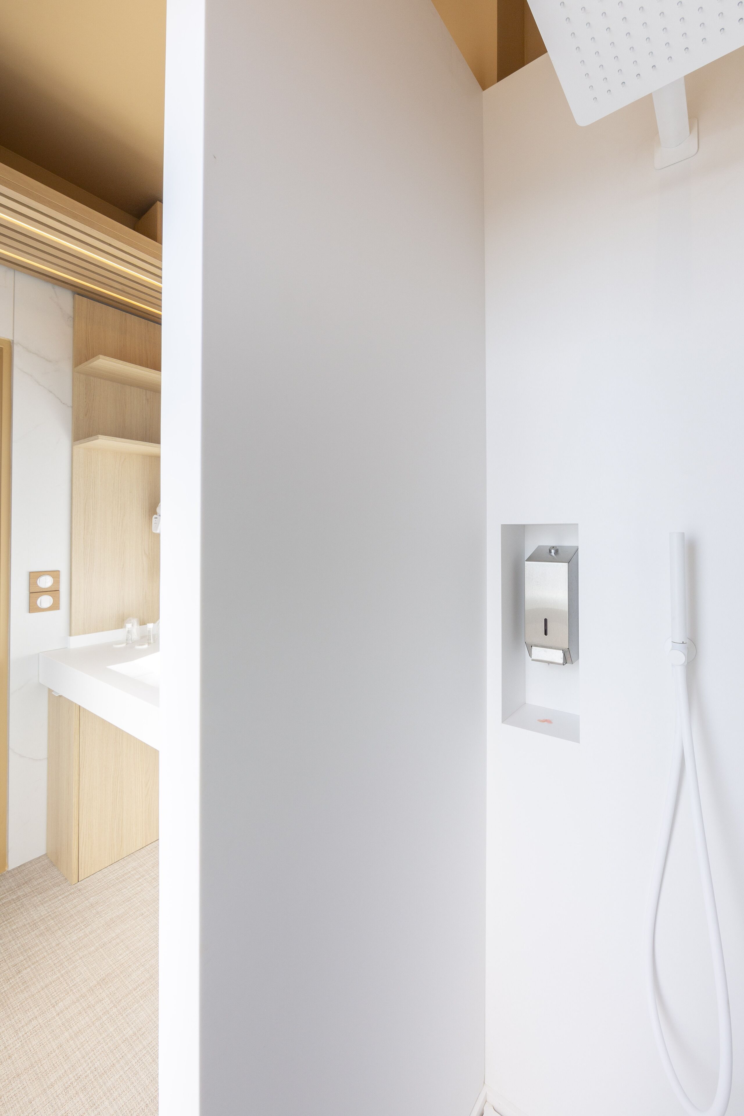 A modern bathroom with a white sink, a shower, and a towel rack.